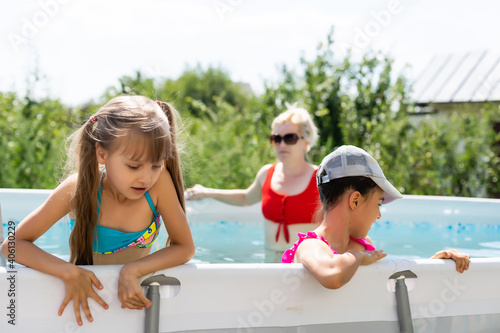 Mother and two daughters playing in pool water.Woman and two girls have fun in home pool splashing water and smiling © Angelov