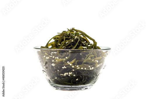 Kelp algae (kelp) in a glass bowl, sprinkled with sesame seeds, isolated on a white background. Salad. Healthy food concept.