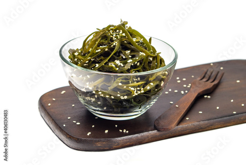 Fotografía Seaweed kelp (Laminaria) in a glass bowl, sprinkle sesame seeds on a wooden board, Isolate on white background