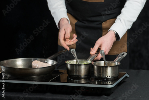man cooking meat and sauce on a induction cooker
