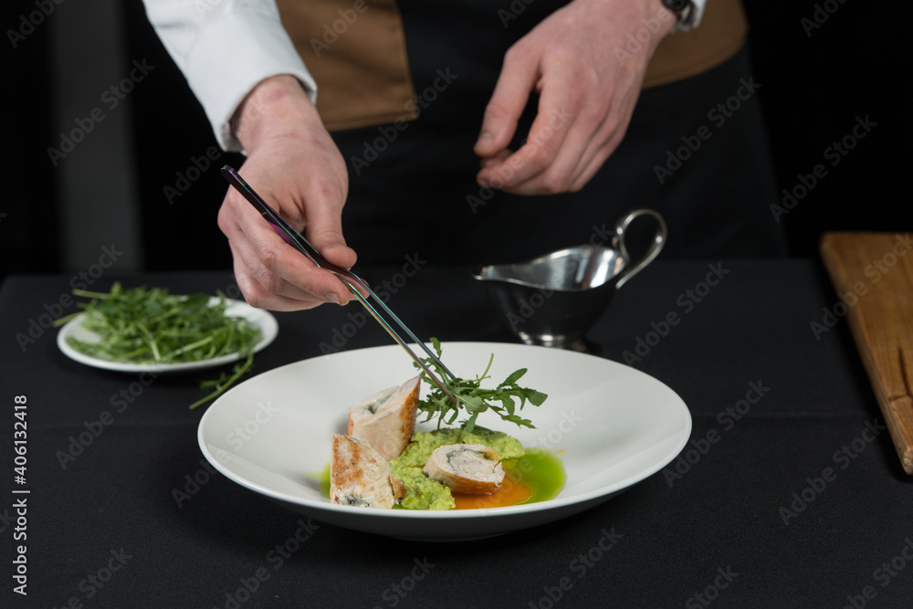 The chef prepares a serving of meatloaf. Putting Arugula over the dish The chef prepares a serving of meatloaf. Putting Arugula over the dish