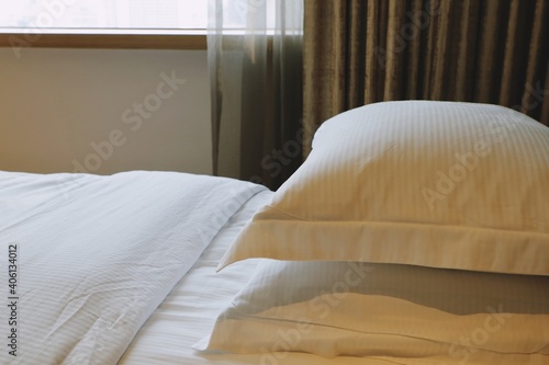 Close up side view of two white soft and clean pillows stacked on white bed , bedsheet and blanket in bedroom.