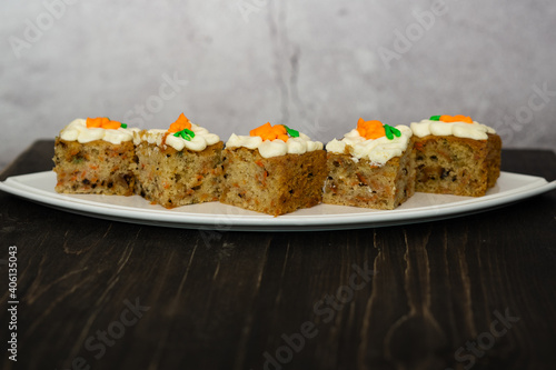 pieces of carrot cakes squares with walnuts and icing cream on a wooden background. selective focus.