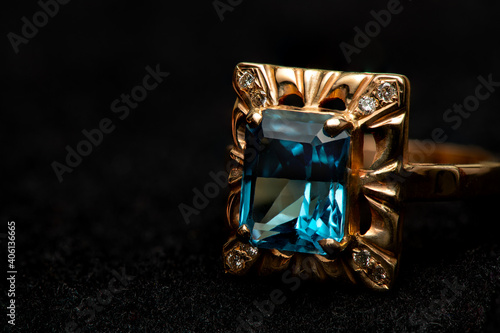 Gold ring with big blue gem and smaller diamonds.