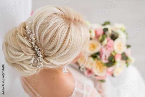 Hairstyle of the bride. A low bun on her blond hair. Rear and top view