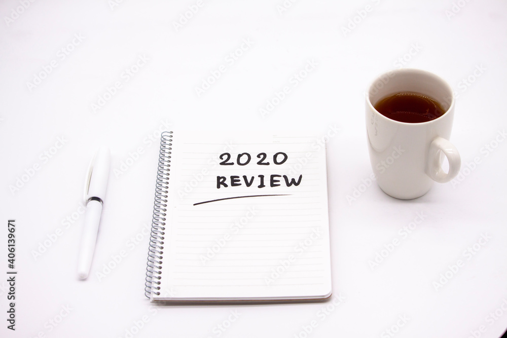 Notepad inscribed 2020 review with pen and tea cup on a white background Notepad inscribed 2020 review with pen and tea cup on a white background