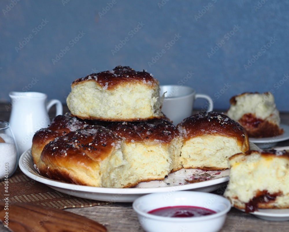 Homemade cake.Buns filled with jam, sprinkled with sesame and icing sugar, on an ancient wooden table, with ingredients and a Cup of tea, with a gray background. Homemade cake.Buns filled with jam, sprinkled with sesame and icing sugar, on an ancient wooden table, with ingredients and a Cup of tea, with a gray background.