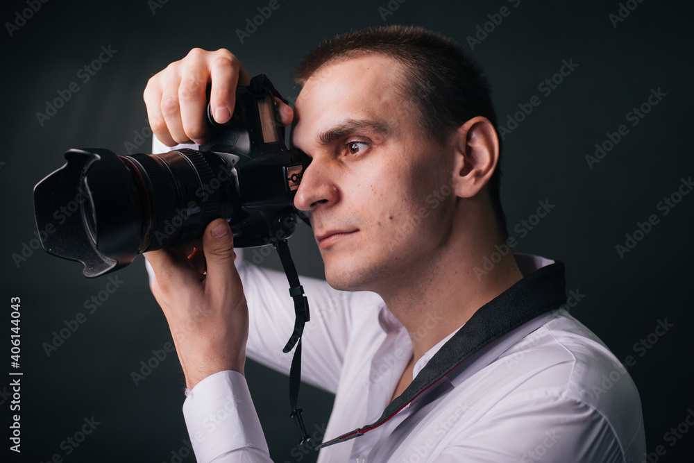 Photographer on a gray background. A man in a white shirt holds a camera in his hands. Studio portrait Photographer on a gray background. A man in a white shirt holds a camera in his hands. Studio portrait