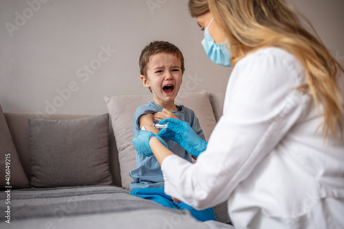 Boy getting a vaccine. A doctor giving a child an injection at home. Little boy getting vaccinated at the Pediatrician's office. Little boy crying. A scared boy about to receive an injection