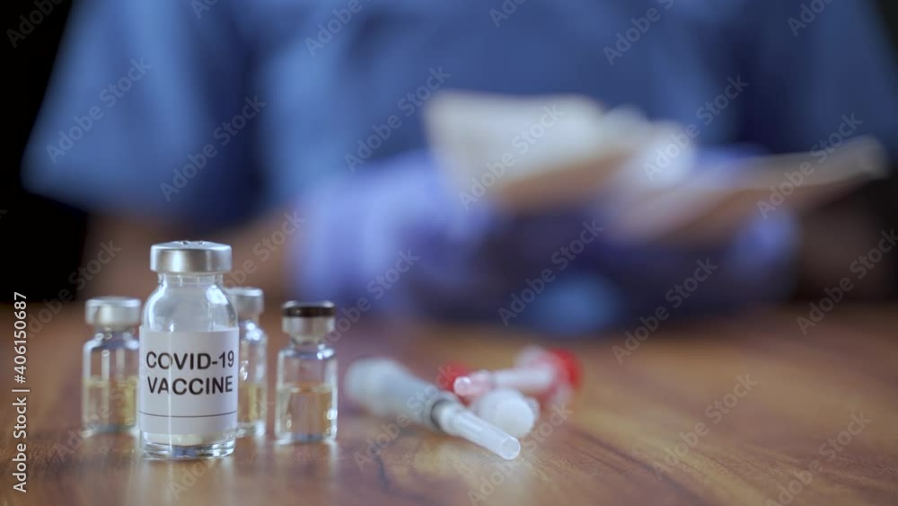 Selective focus on Covid-19 Coronavirus vaccine bottle, Doctor counting money after selling vaccinations illegally - Concept of Covid-19 coronavirus vaccination bribery and corruption Selective focus on Covid-19 Coronavirus vaccine bottle, Doctor counting money after selling vaccinations illegally - Concept of Covid-19 coronavirus vaccination bribery and corruption