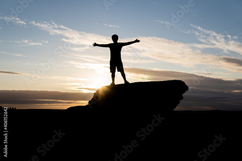 Man sunset silhouette on top of rock 