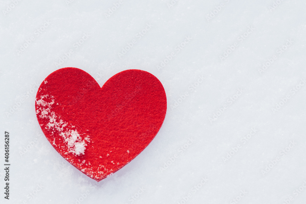 Close up of red heart from felt on snow