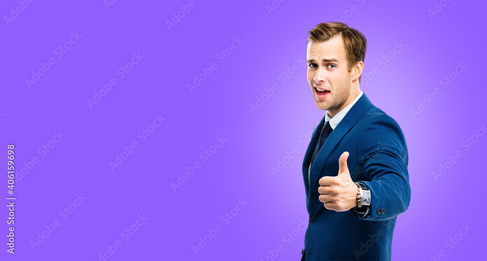 Excited businessman showing thumbs up like hand sign gesture, blue confident suit, over purple violet color background. Handsome happy man. Copy space for slogan or text. Excited businessman showing thumbs up like hand sign gesture, blue confident suit, over purple violet color background. Handsome happy man. Copy space for slogan or text.