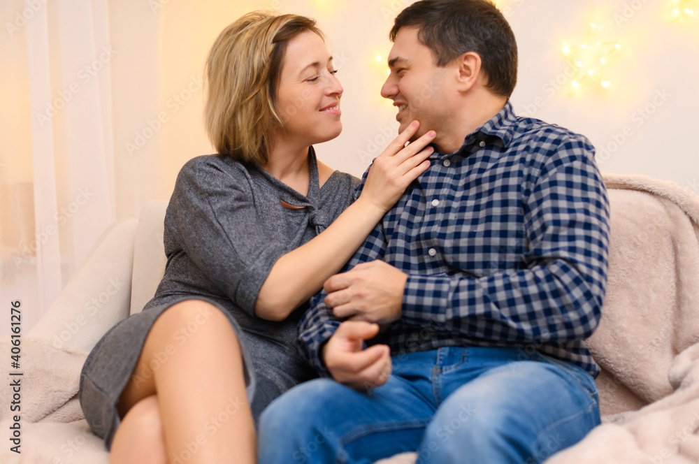 portrait of adult couple sitting on a sofa at home