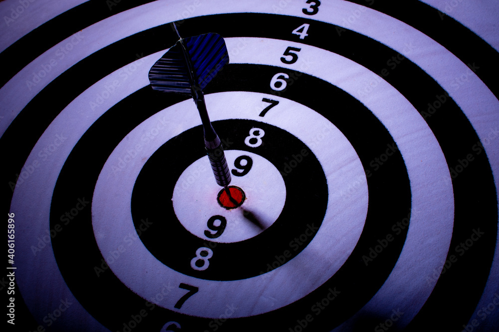 Blue dart spiked in the center of black and white target. Selective focus. Blue dart spiked in the center of black and white target. Selective focus.