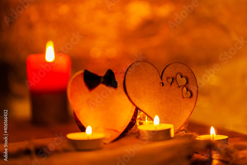Two hearts and candles on wooden boards. St Valentine's day greeting card with candles and hearts on a blurred background. Love story concept