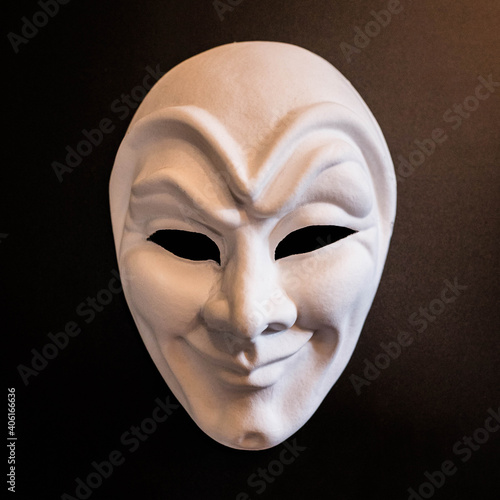 White theatrical mask of the Joker on a black background photo