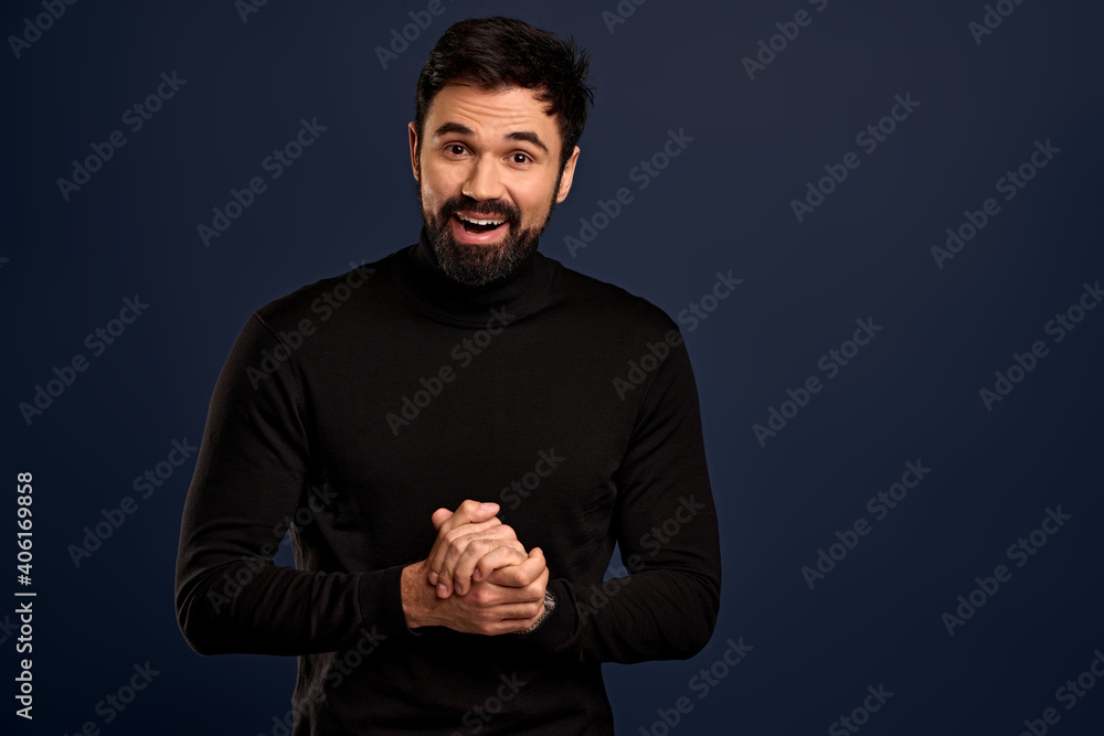 Handsome good-looking stylish caucasian guy in black high neck sweater, rubbing hands and smiling politely, want sale something, making good deal,suggesting buy product, stand Pacific Blue background