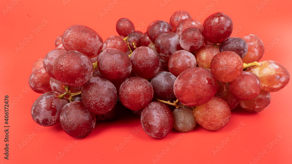 Fresh red grapes isolated on pink background. Selective focus on the fresh red grapes.
