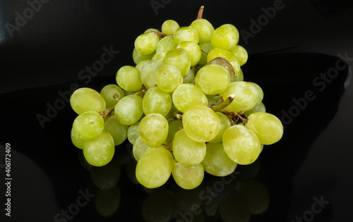 Branch of ripe green grapes isolated on a black background. Selective focus on the green grape