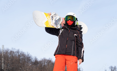 senior woman in sports wear protective face mask holding snowboard
