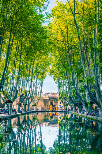 Street life around a water reservoir with beautiful green platanus trees in the provencal village of Cucuron, France