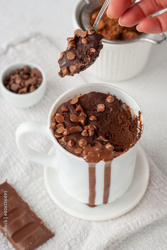 Chocolate mug cake in white cup with chocolate drops and coca powder Photos  | Adobe Stock
