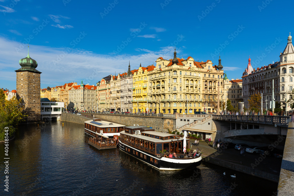 Picturesque view of Prague embankment on bank of Vltava river with peculiar architecture on autumn day, Czech Republic