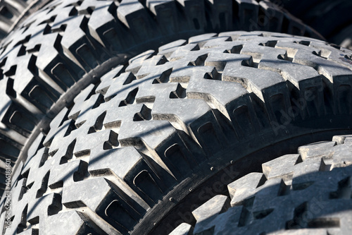 Recycling of car tires for trucks. That's a lot of black bald rubber tires lying outside in an open warehouse. Close-up