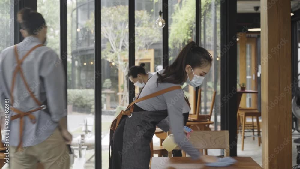 restaurant workers wearing a protective face mask to prevent coronavirus spread and cleaning table before the open. slow motion restaurant workers wearing a protective face mask to prevent coronavirus spread and cleaning table before the open. slow motion