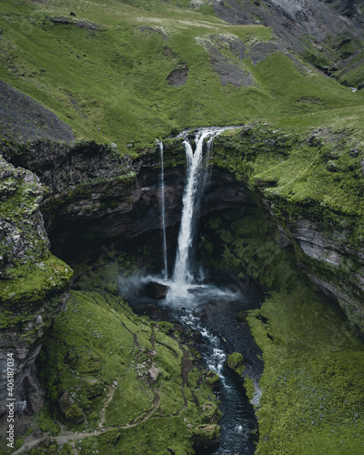 Photo Breathtaking view of a powerful waterfall surrounded by rocky cliffs in Iceland