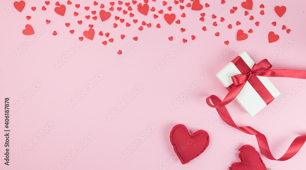 Valentine's day. Rain of red hearts on a pink background. Gift package with ribbon bow. Coppy space. Flat lay, top wiew
