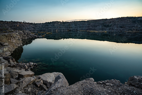 Old flooded stone quarry surrounded by stone waste from a mine work against a beautiful night sky © YouraPechkin
