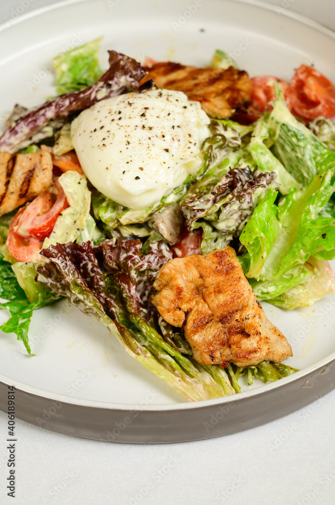 Caesar salad with croutons, quail eggs, cherry tomatoes and grilled chicken in white table Caesar salad with croutons, quail eggs, cherry tomatoes and grilled chicken in white table