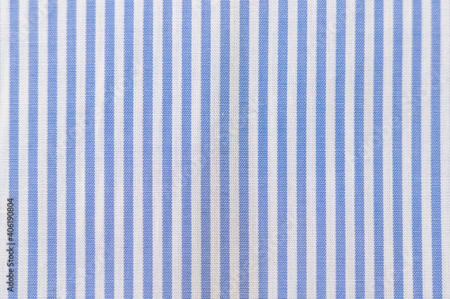 Striped textile pattern of a blue white business shirt. Fabric structure closeup of fashion clothing.