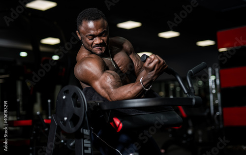 Muscular bodybuilder trains on modern gym background. Strong hands of brutal sportsman. Closeup.