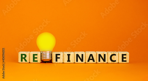 Refinance symbol. Wooden cubes with word 'refinance'. Yellow light bulb. Beautiful orange background. Business and refinance concept. Copy space. photo