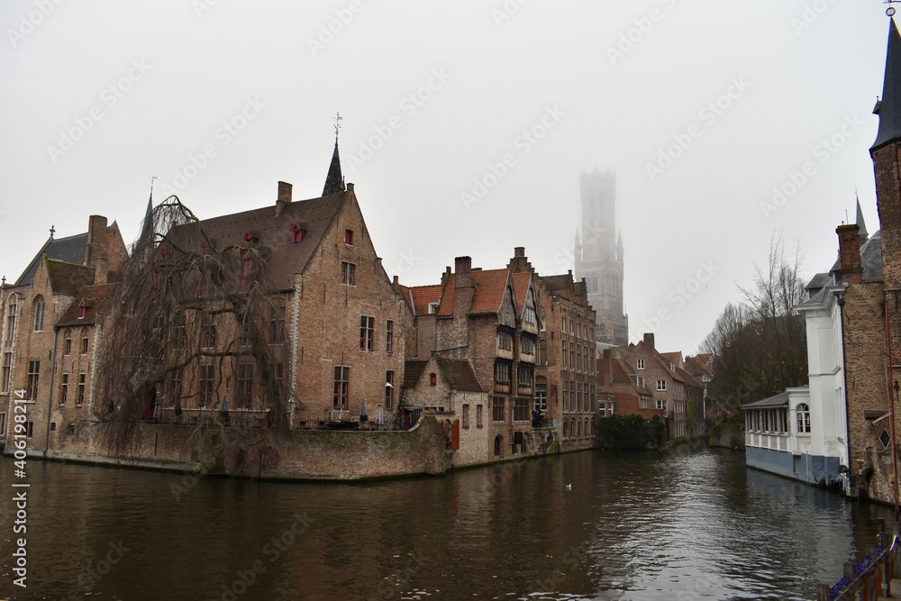 Famous picture spot in Brugge with the Belfry of Brugge in the background among fog Famous picture spot in Brugge with the Belfry of Brugge in the background among fog