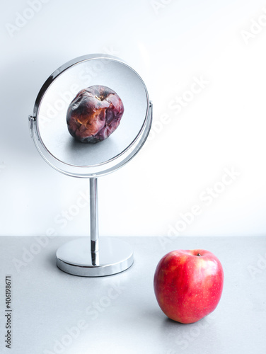 Rotten apple reflection on the mirror, depression and narcissism concept, young vs old