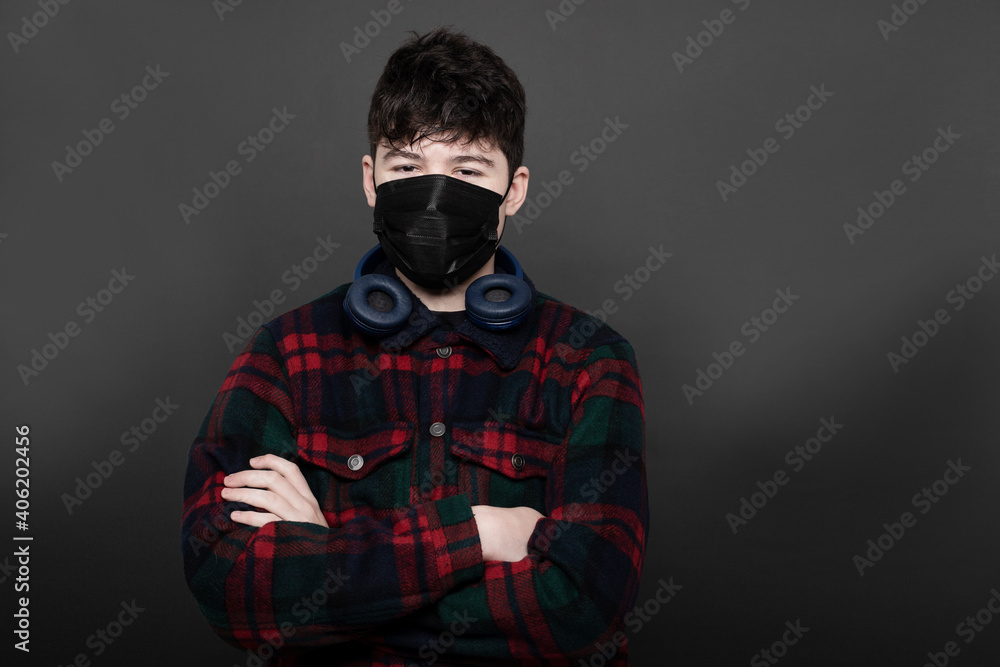 teenager with headphones and medica mask in studio with grey background