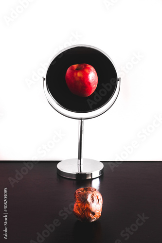 Rotten apple reflection in the mirror, depression and narcissism concept, old and young