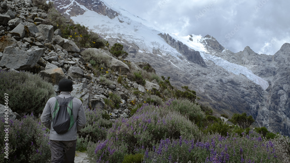 Hiker along alpine landscape and snowy peaks on the way to Lagoon 69 at Huascaran National Park, Peru.