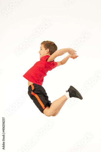 Cute sporty boy jumping against white background