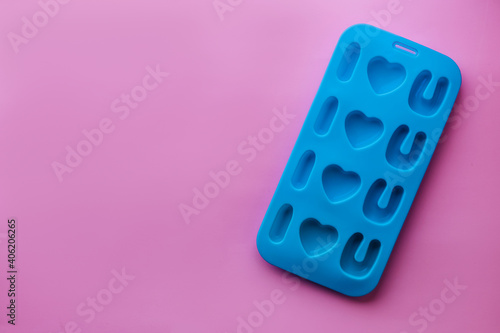 top view of blue silicone mold for ice or candies in shape of phrase I love you for handmade dessert on valentine day gift. pink background. concept of Valentine's Day, Love and Mother day. copy space