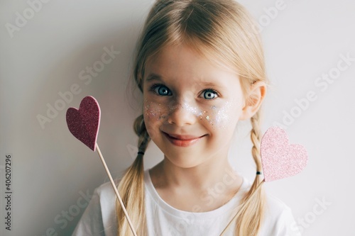 Lovely little girl with paper hearts. Valentines day. Portrait of a child holding pink valentine.