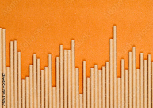 row of paper craft cocktail tubes of different heights on orange paper background