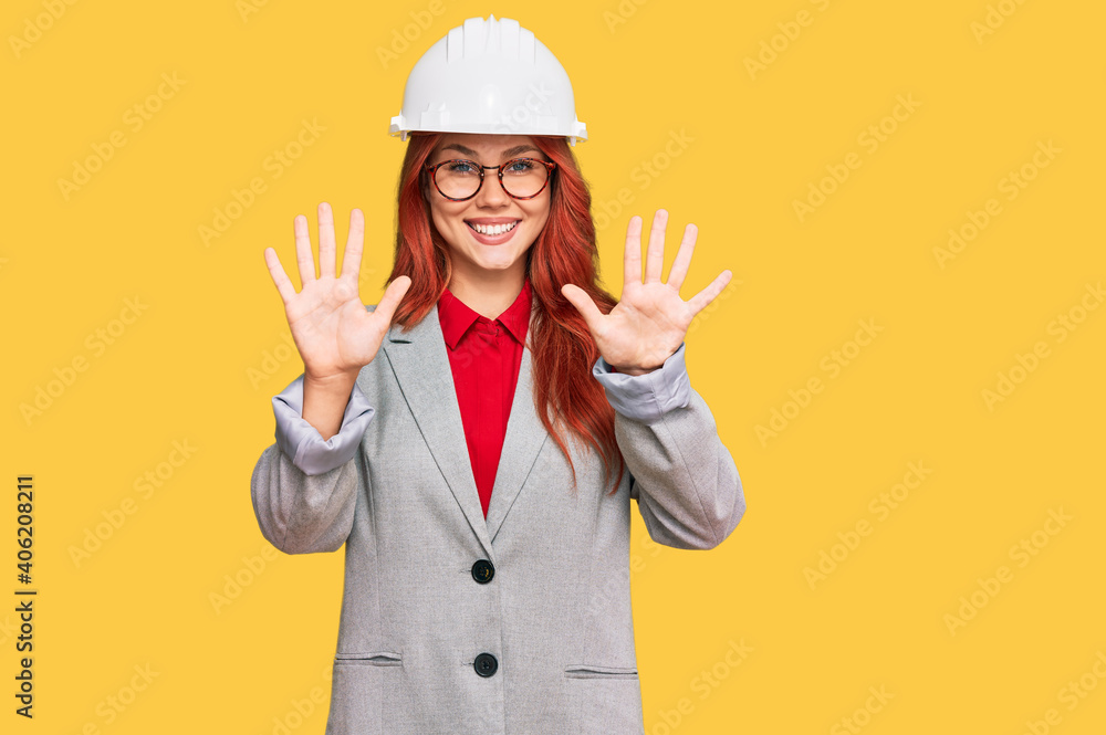Young redhead woman wearing architect hardhat showing and pointing up with fingers number ten while smiling confident and happy. Young redhead woman wearing architect hardhat showing and pointing up with fingers number ten while smiling confident and happy.