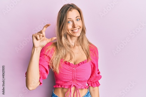Beautiful caucasian woman wearing casual clothes smiling and confident gesturing with hand doing small size sign with fingers looking and the camera. measure concept. © Krakenimages.com