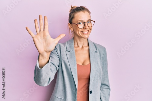 Beautiful caucasian woman wearing business jacket and glasses showing and pointing up with fingers number five while smiling confident and happy.