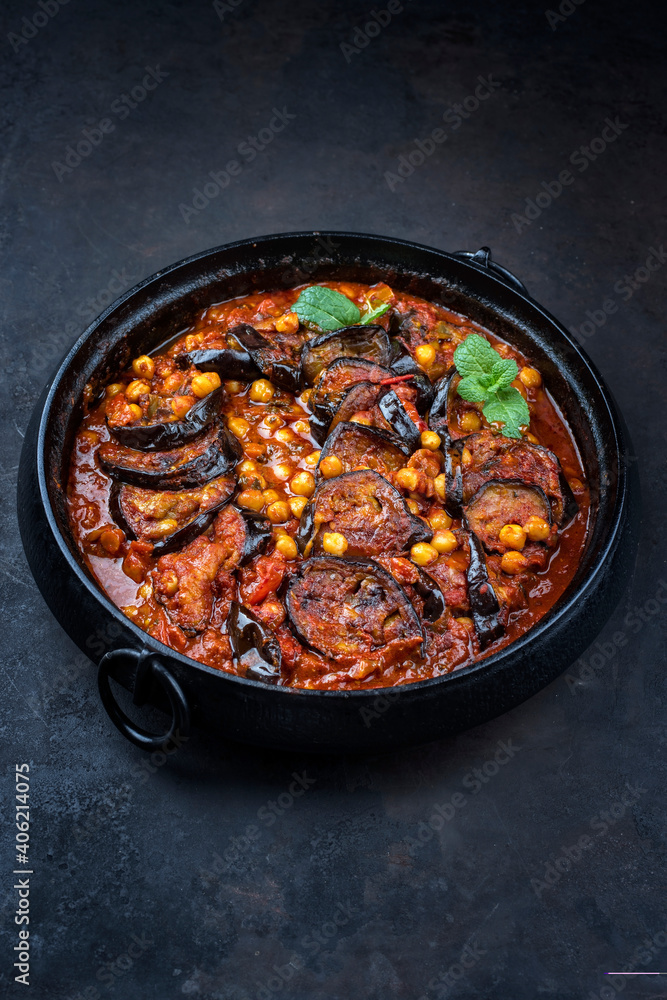 Modern style slow cooked Lebanese vegetarian eggplant stew maghmour served with chickpeas as close-up in a design pot with copy space Modern style slow cooked Lebanese vegetarian eggplant stew maghmour served with chickpeas as close-up in a design pot with copy space
